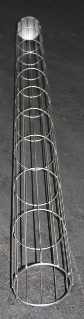 Ein metallener, zylindrischer Drahtkäfig mit Ersatzteilen liegt auf einer dunklen Fläche.